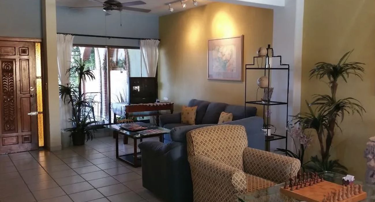 The living room at Colibrí Centro with sofas, a chess table and the carved wooden front door