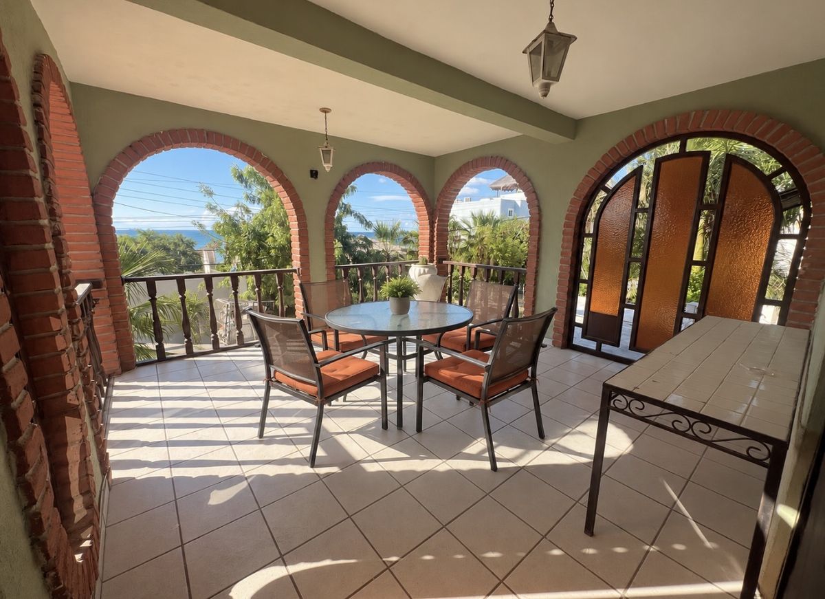 Cacti Room private covered balcony with brick arches, a table and chairs, and a glimpse of the water beyond