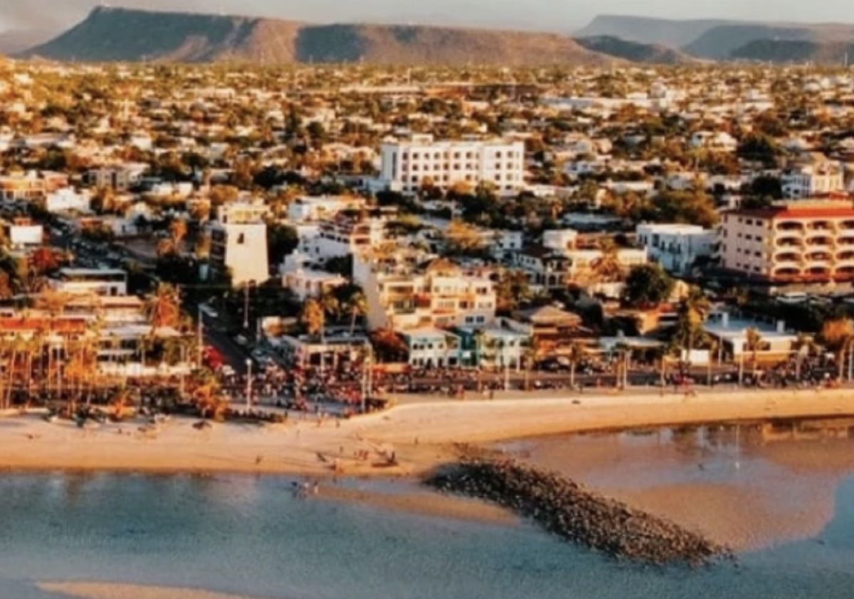 Aerial view of central La Paz at golden hour: the Malecón, the beach and the desert mesas behind the city