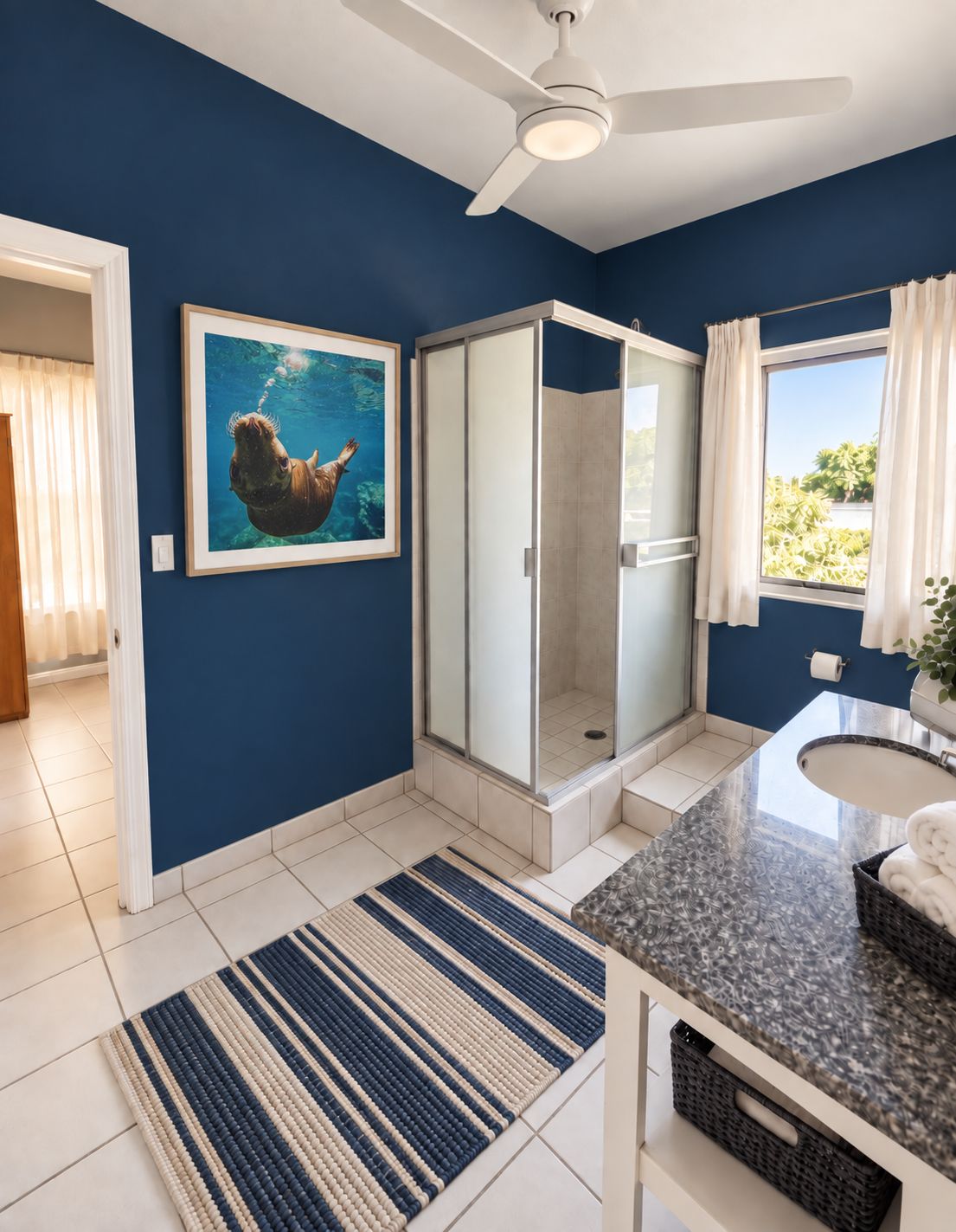 The Ocean Suite's Jack-and-Jill bathroom with navy walls, a glass shower and sea lion art