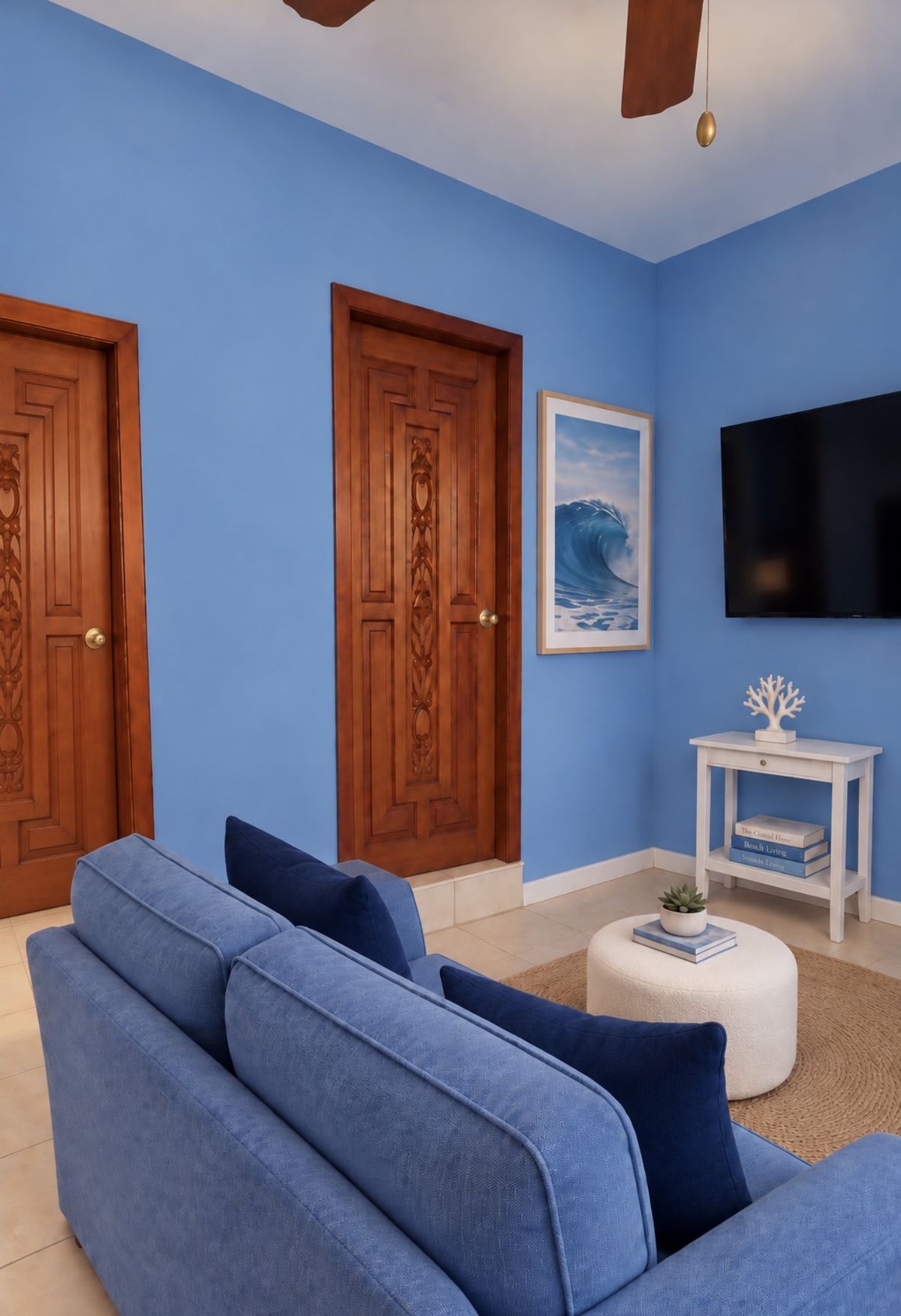 Wave Room corner with a blue sofa, a white side table, a wall-mounted TV and a framed wave print