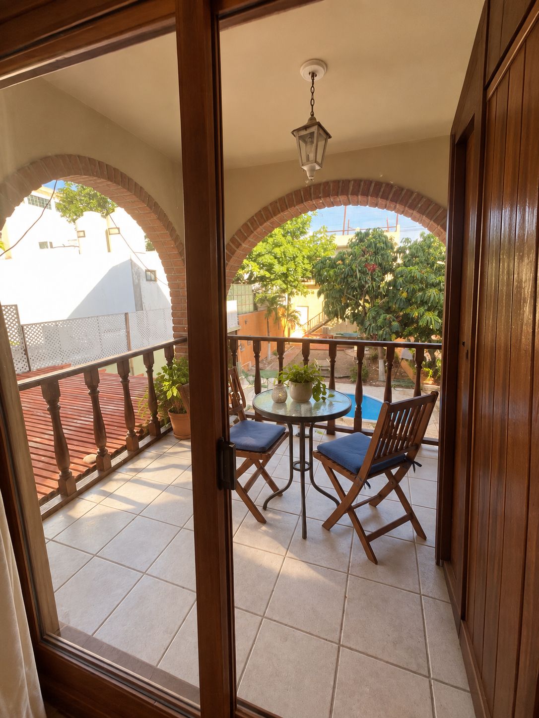 Wave Room balcony through wooden doors: a bistro table and chairs under a brick arch
